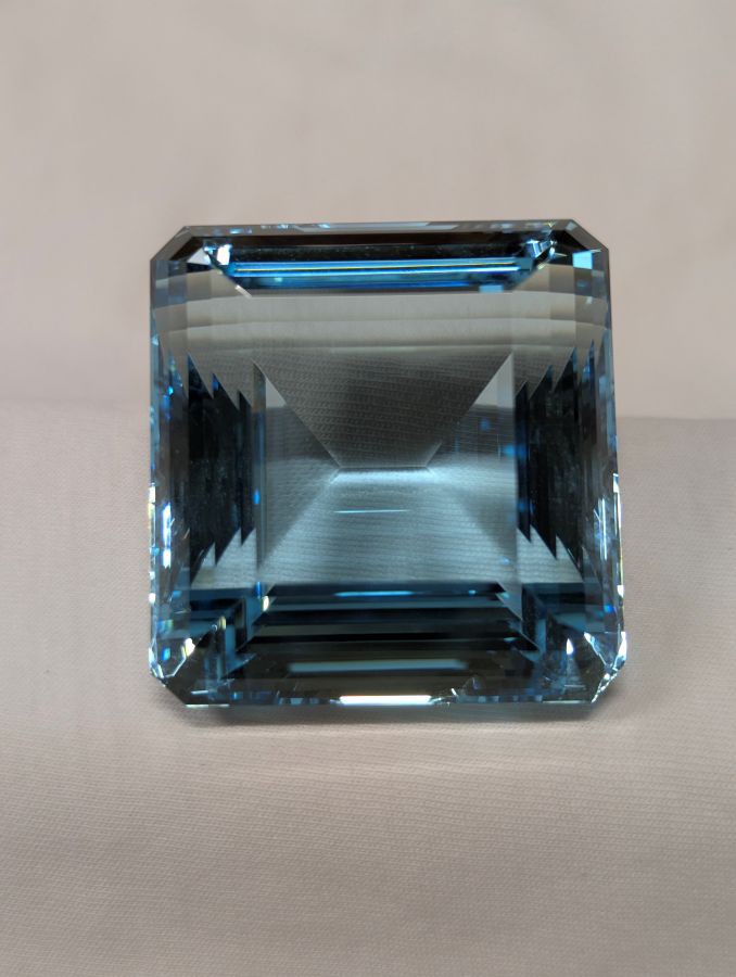 Auf dem Bild ist ein Aquamarin zu sehen, facettiert im Treppenschliff geschliffen, als Achteck. Der Stein ist fast quadratisch und zeigt eine schöne hellblaue Farbe.