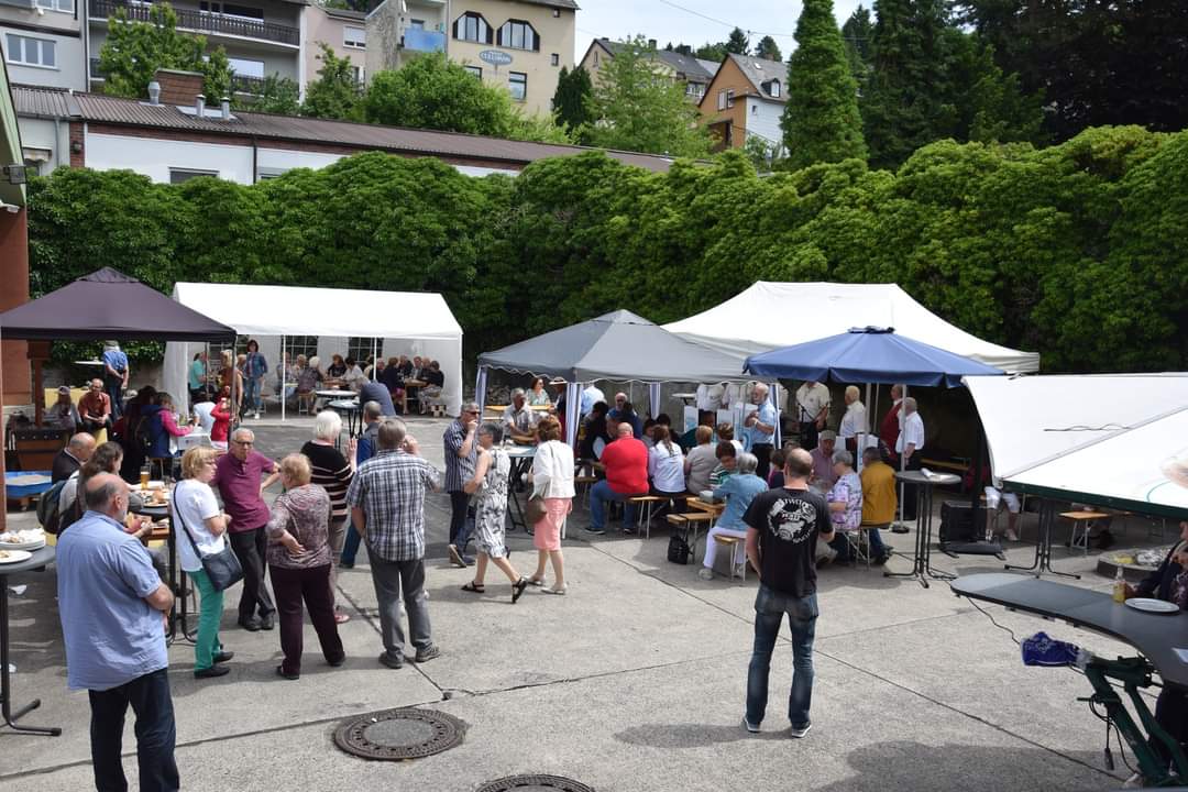 Man sieht viele Menschen aus einem Platz mit Festzelten